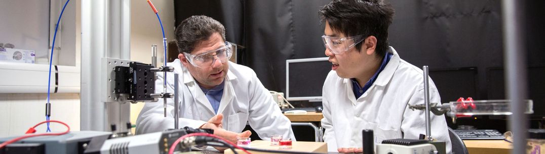 Professor Joshua Edel and a student discuss an experiment involving batteries